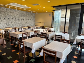 Ein Restaurant mit mehreren Tischen und Stühlen, einer Wand mit Musterung und einer Uhr an der Wand.