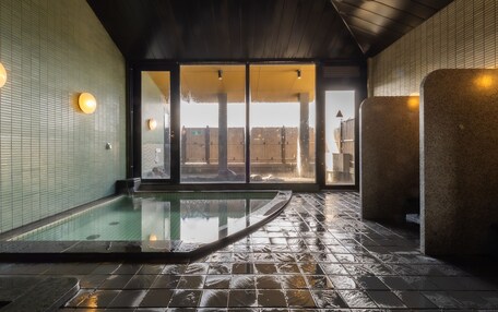 A spa area with a hot tub, tiled walls, and a wooden ceiling.