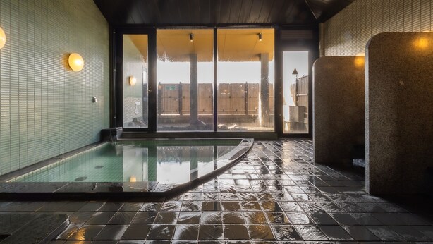A spa area with a hot tub, tiled walls, and a wooden ceiling.