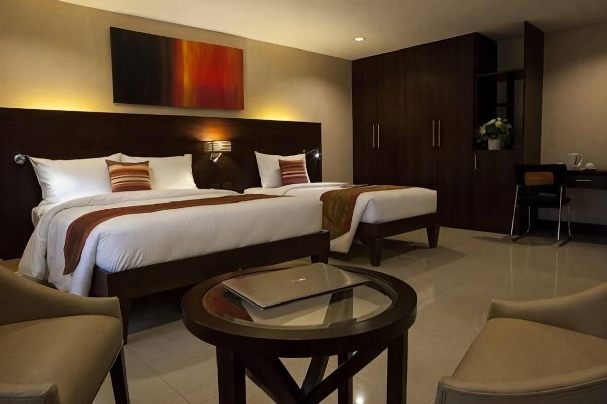 Een hotelkamer met twee bedden, een bureau, een stoel en een ronde tafel.