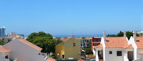 Zona residencial costera con edificios blancos y tejados de tejas rojas, destacando un edificio amarillo en el centro.