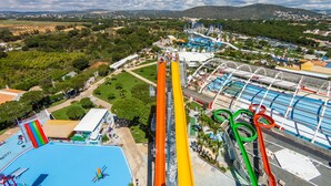 A water park with a tall water slide, multiple pools, and a view of the surrounding landscape. - Algardia Apartments (Loulé)