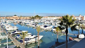 A marina with numerous boats docked, palm trees, and a clear blue sky. - Algardia Apartments (Loulé)