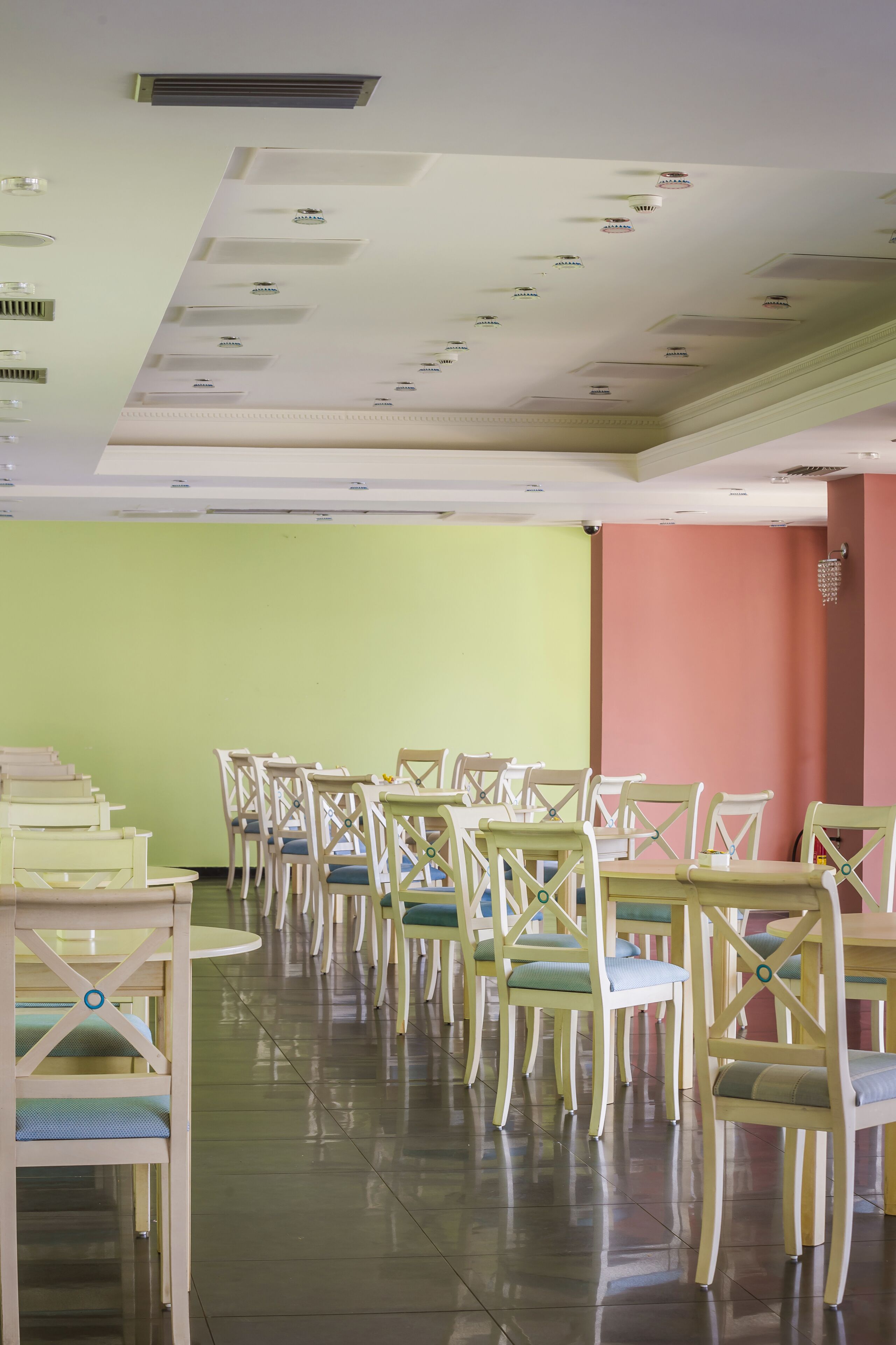 A dining area with multiple tables and chairs, a green wall, and a red accent wall.
