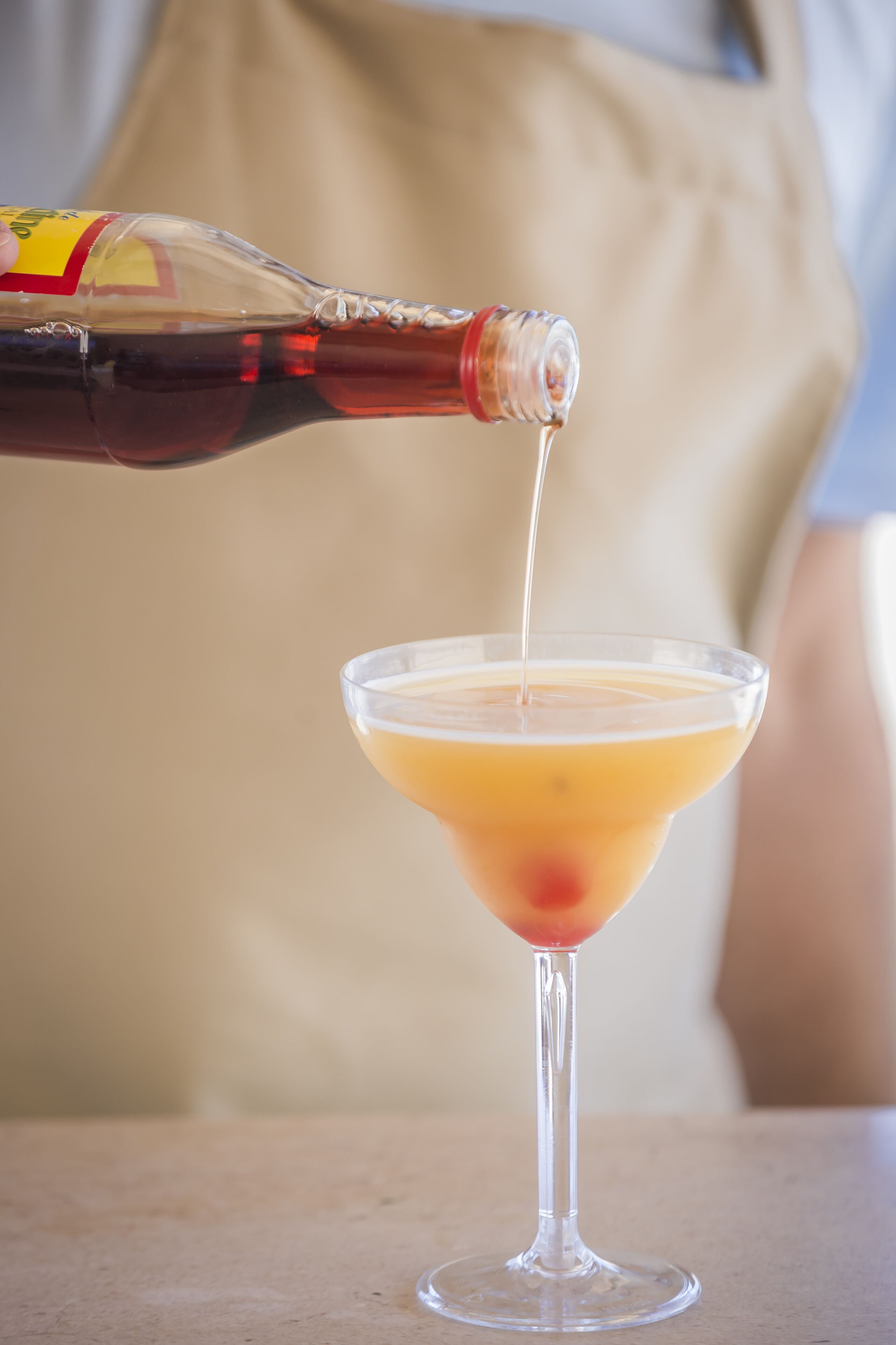 A bottle being poured into a martini glass.
