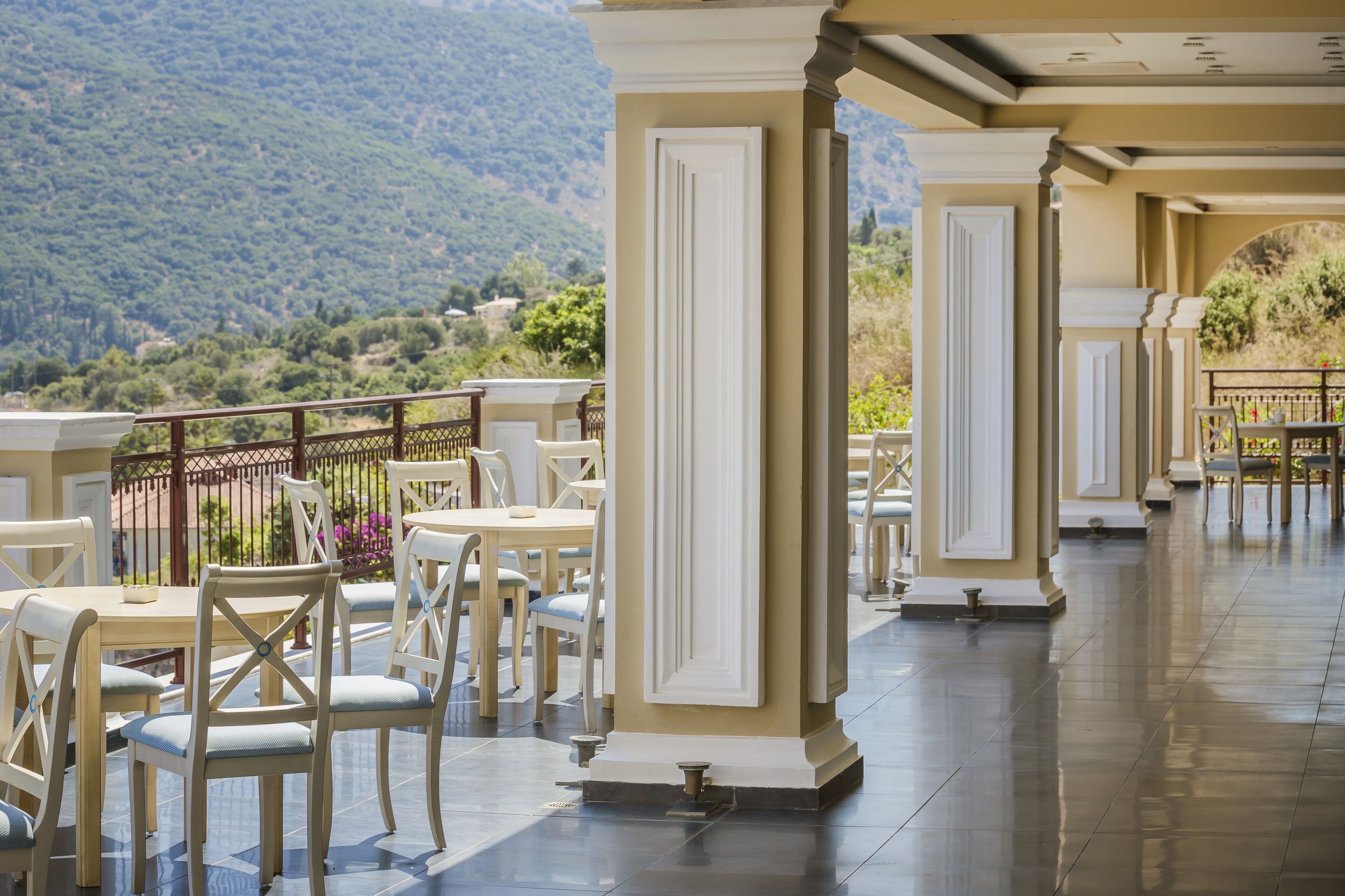 Una terraza con mesas y sillas, con vistas a un paisaje montañoso.