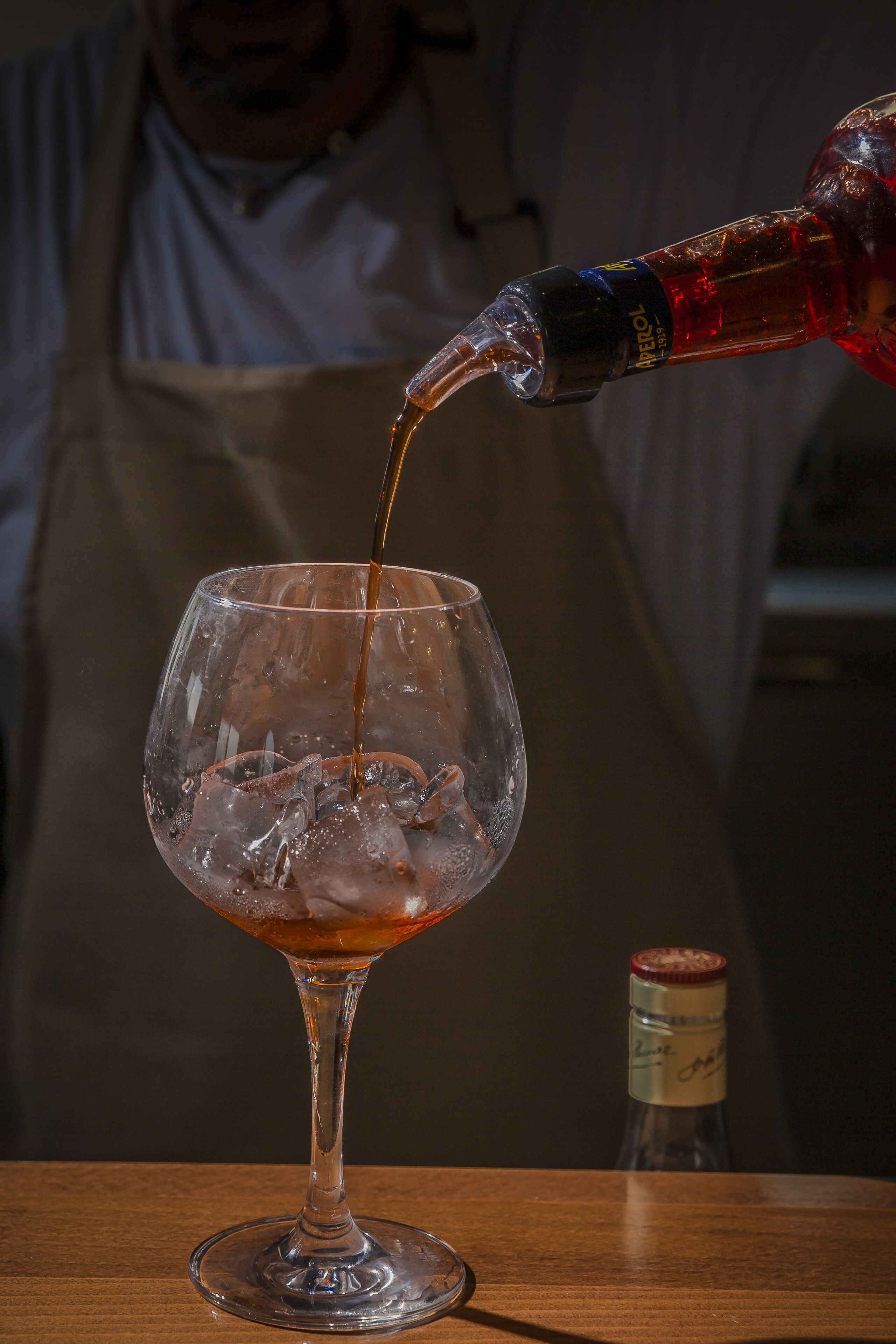 A glass of whiskey being poured into a glass with ice cubes.