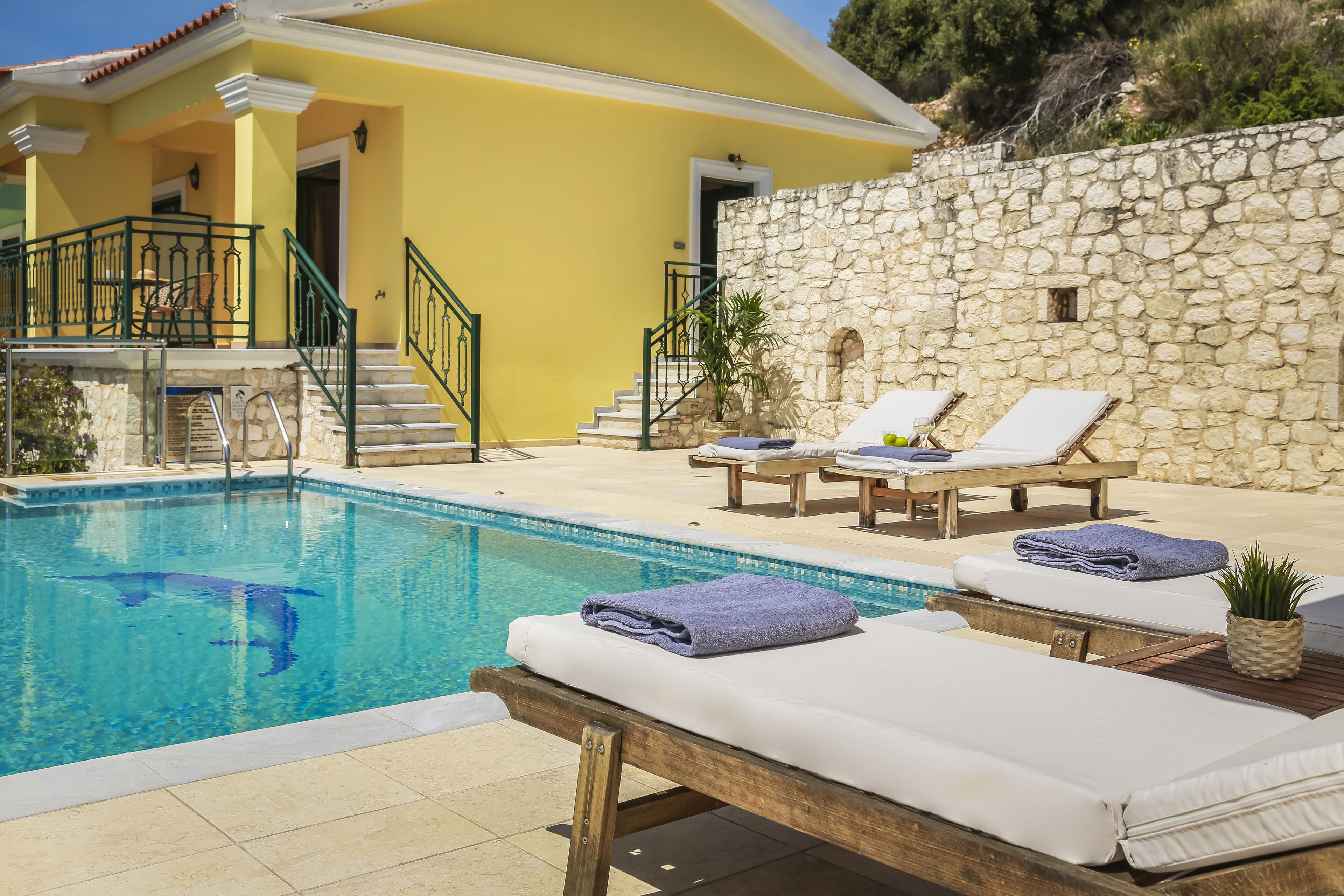 Un espace piscine avec des chaises longues et un mur en pierre.