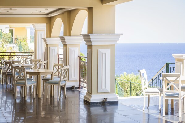 A terrace with white chairs and tables, overlooking a body of water.