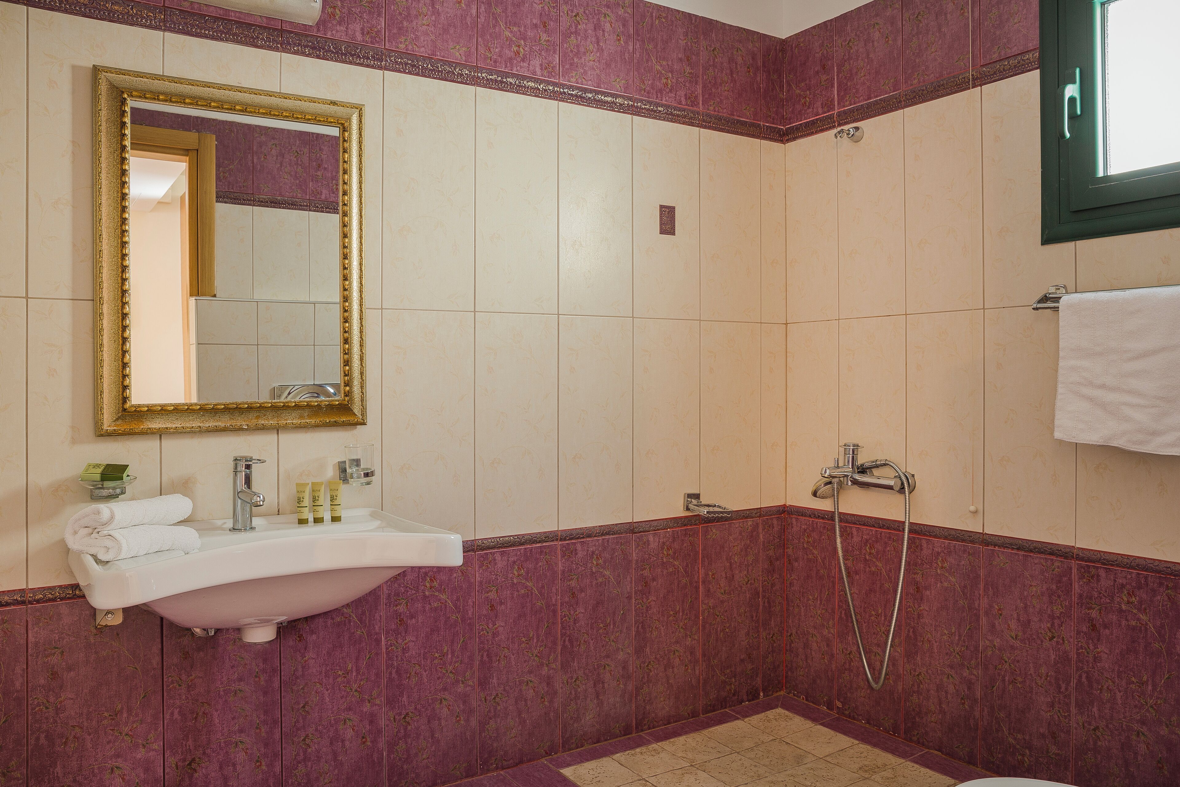 A bathroom with a sink, mirror, and shower.