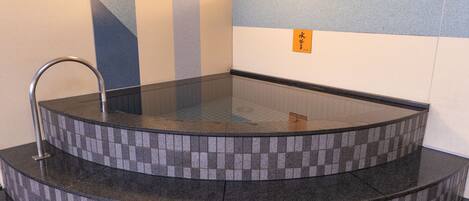 A hot tub with a tiled surround and a metal faucet.