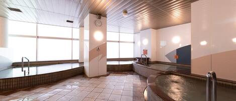 Une piscine intérieure spacieuse, dotée d’une eau claire, de carrelages et d’un design moderne au niveau du plafond.