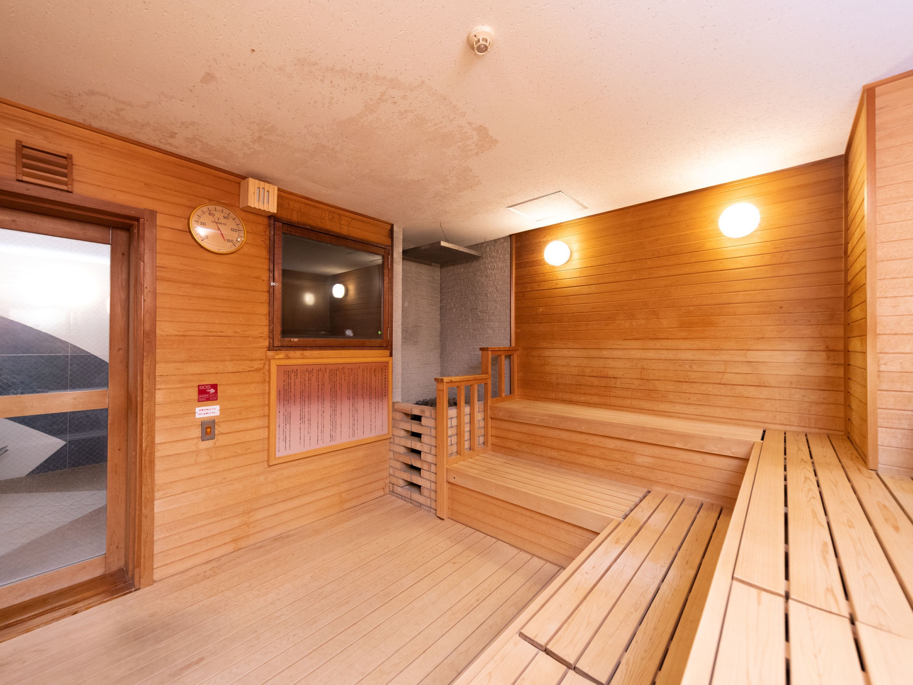 Una sauna de madera con un banco, una ventana pequeña y un reloj en la pared.