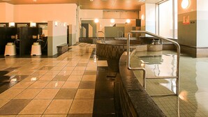 A public sauna with tiled floors, a central hot tub, and multiple shower stalls. - APA Hotel Fukui Katamachi (Fukui)