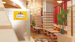 A restaurant interior with a sign for 'Ashirwad Indian Restaurant'. Tables and chairs are arranged in a dining area with a patterned floor. - APA Hotel Fukui Katamachi (Fukui)