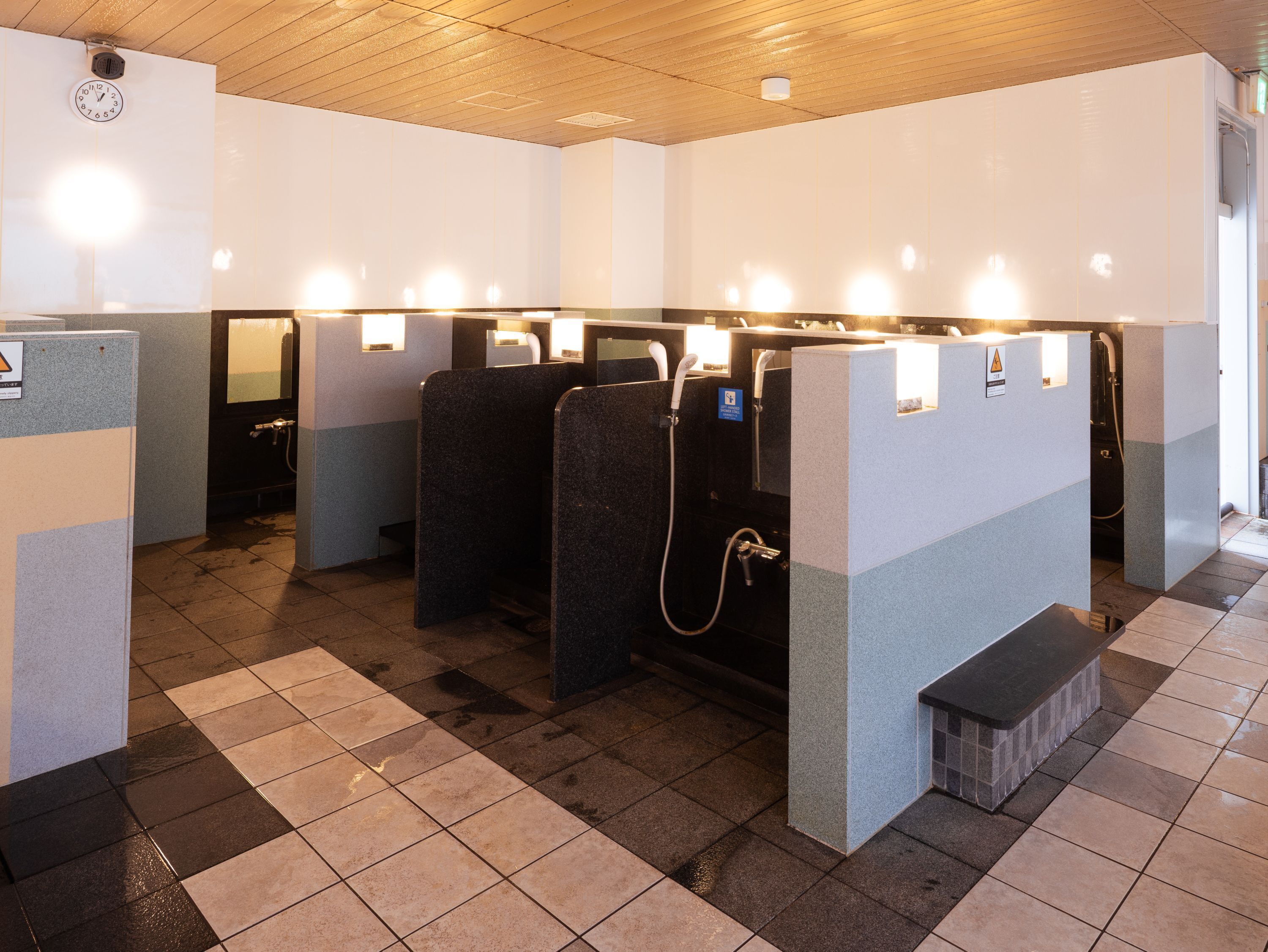 A public restroom with multiple cubicles, each equipped with a hand dryer and a paper towel dispenser.