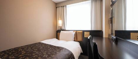 Habitación de hotel con una cama grande, un escritorio y una silla. Hay una ventana con cortinas, una lámpara y un espejo en la pared.