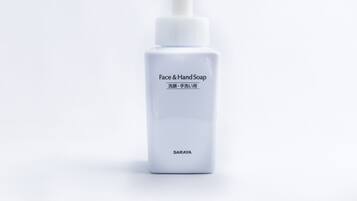 A white bottle of face and hand soap with a pump dispenser.