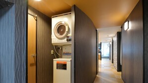 Ein Hotelkorridor mit Waschmaschine und Trockner, Holzwänden und einem Schachbrettmuster Boden.
