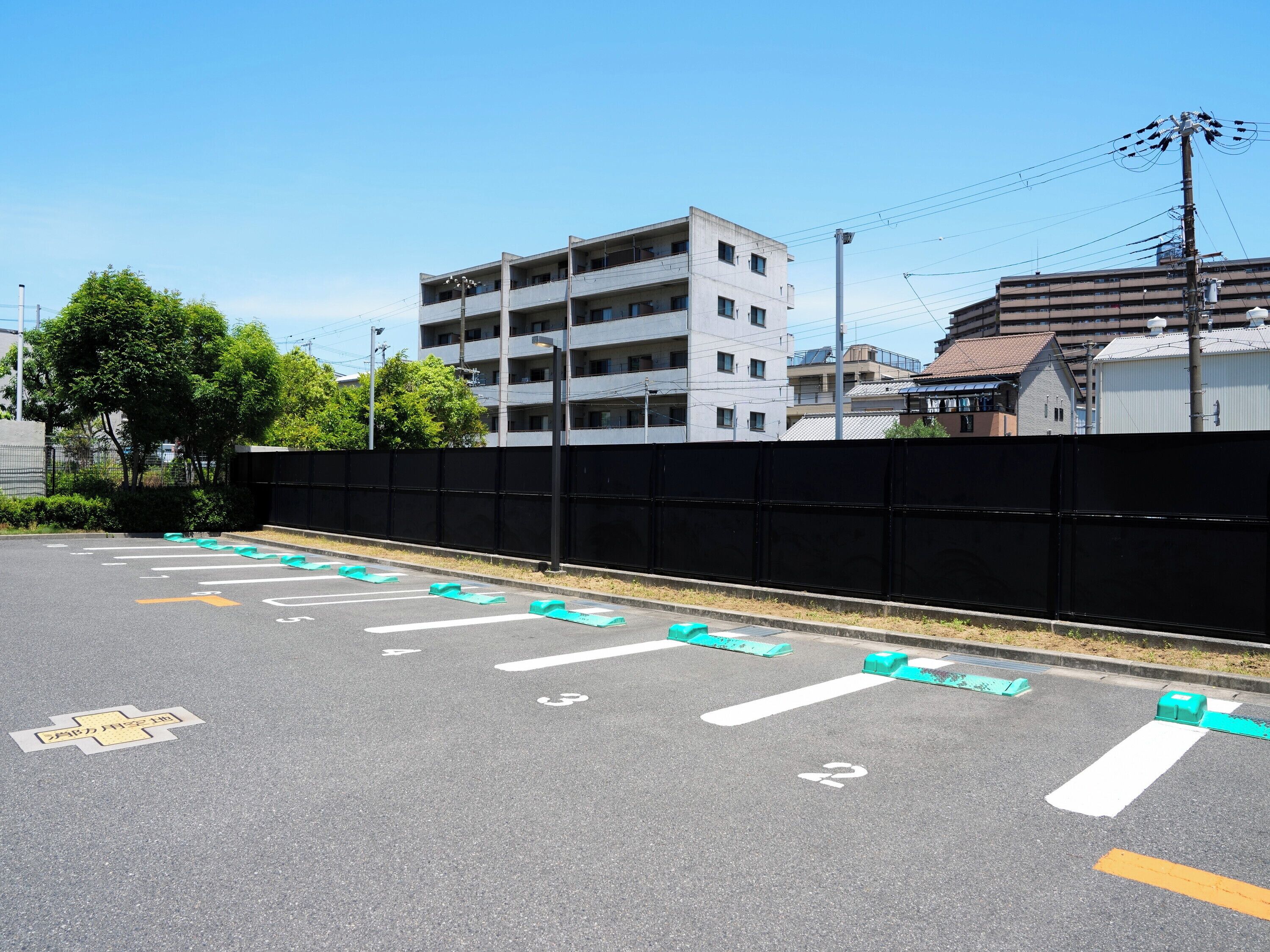 A parking lot with marked spaces and a building in the background.