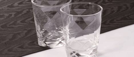 Dos vasos de vidrio transparente sobre una superficie blanca con un fondo oscuro estampado.