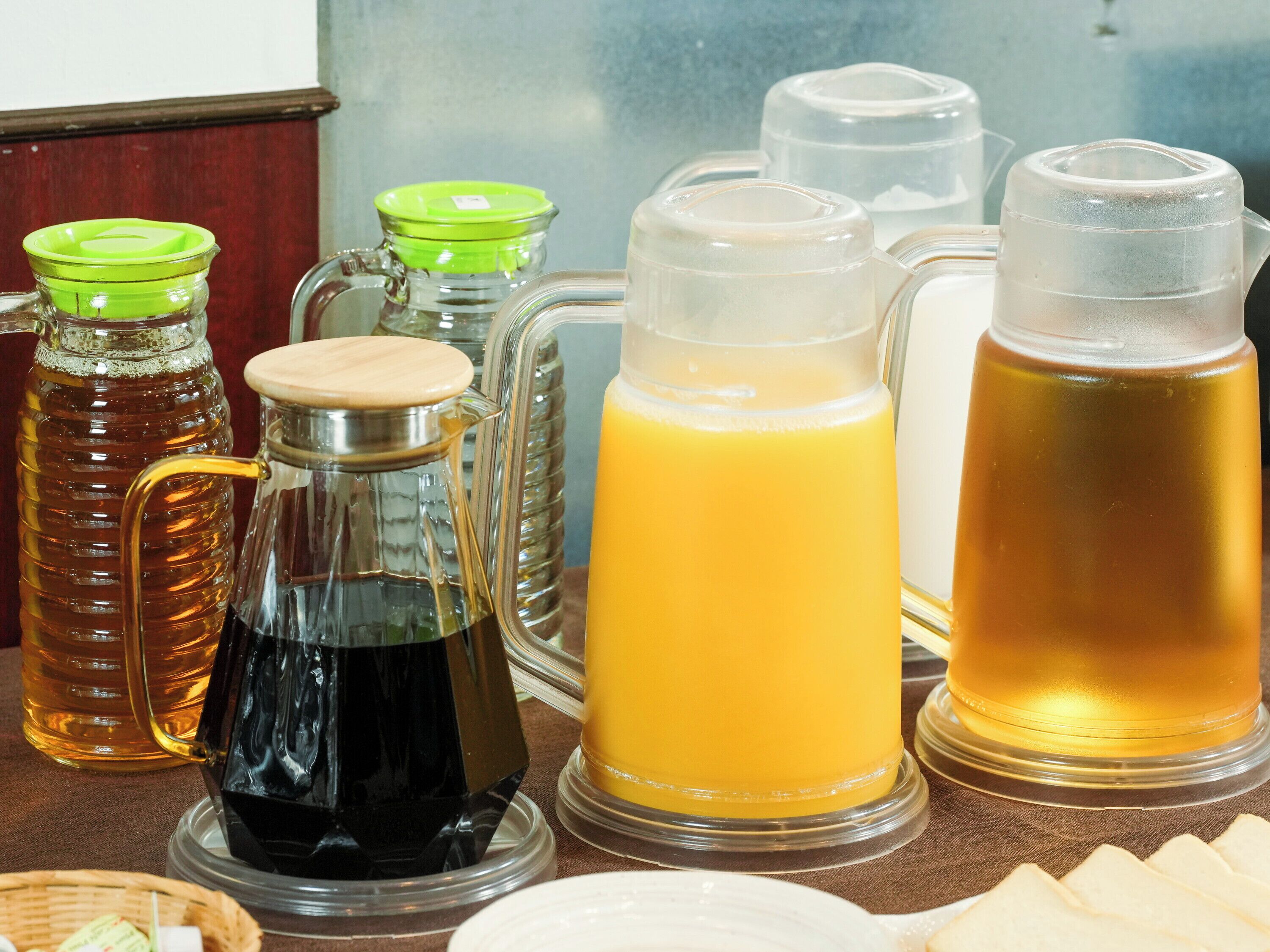 A variety of beverage dispensers, including a honey dispenser, a coffee pot, and several pitchers of orange juice.