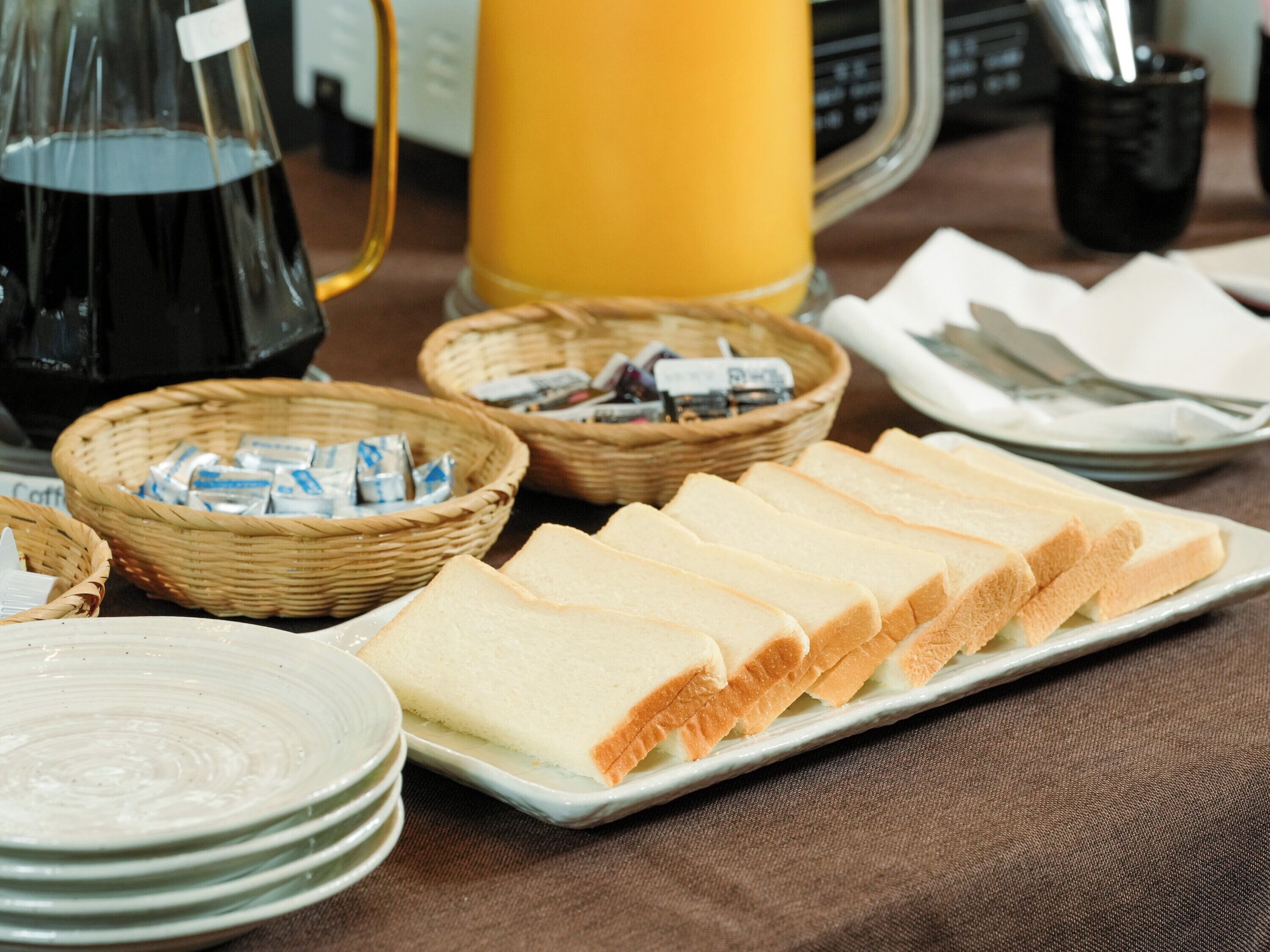 A breakfast setting with bread, coffee, and juice.