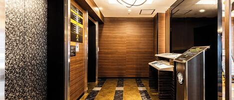 A modern elevator interior with a patterned wall, a marble floor, and a digital display.
