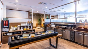 Ein moderner Frühstücksbereich mit Buffet, Kaffeeautomaten und einer Sitzgelegenheit mit Bank.