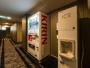 Ein Getränkeautomat mit der Aufschrift 'KIRIN' und ein Eismaschine in einem Hotelgang.