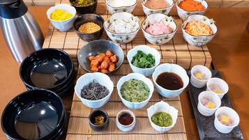 A variety of food items and condiments arranged on a table, including bowls of rice, vegetables, and sauces.