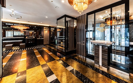 A hotel lobby with a check-in counter, a reception desk, and a chandelier.