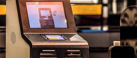 A self-service kiosk with a screen, card reader, and receipt slot.