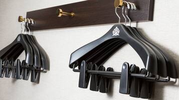 Two black coat hooks mounted on a wooden wall.