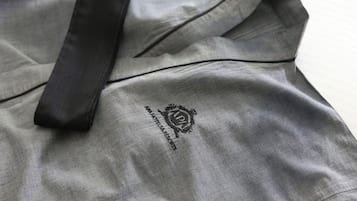 Ein grauer Hotelbademantel mit schwarzem Band und einem Aufdruck mit dem Schriftzug „APHA HOTEL & SPA“.