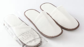 Um par de chinelos brancos com detalhes marrons, embalados em um saco plástico transparente com etiqueta.