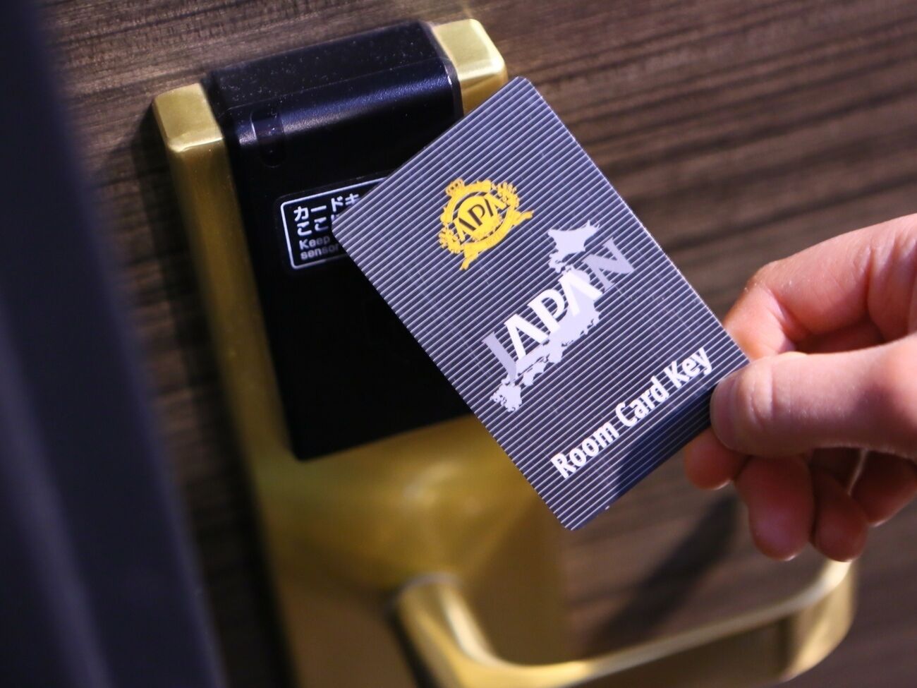 Une main tenant une carte-clé de chambre d’hôtel, sur laquelle on peut lire les mots « JAPON » et « Carte-clé de chambre ».
