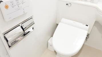 A modern bathroom with a toilet, a paper towel dispenser, and a hand dryer.