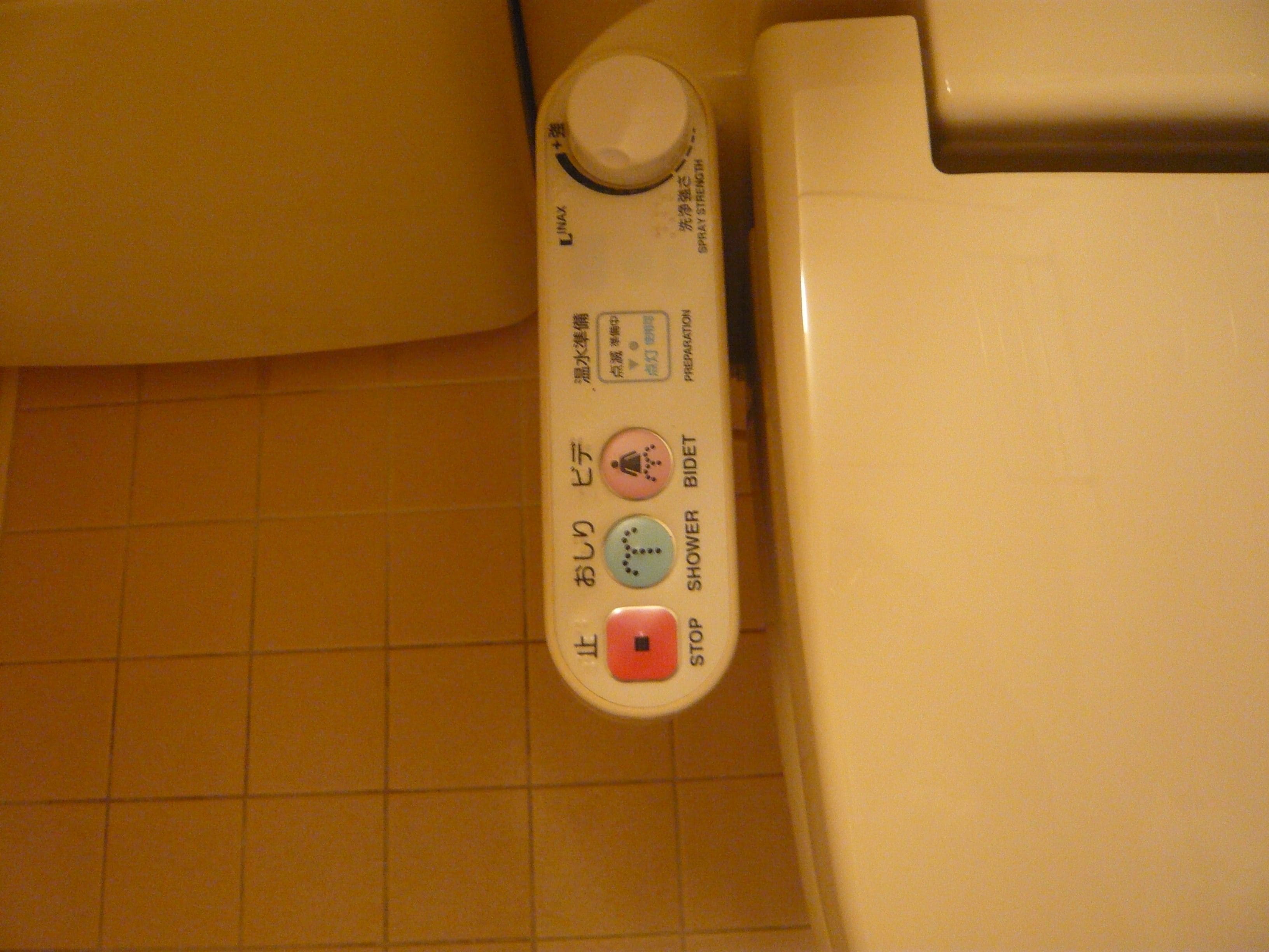 A control panel with Japanese text, a button labeled "STOP," and a button labeled "SHOWER BIDET."