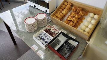 A breakfast buffet with croissants, buns, and condiments.