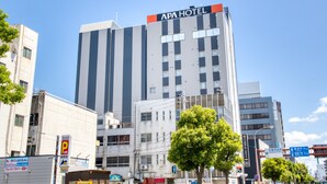Un immeuble à plusieurs étages, sur lequel on peut lire l’inscription « APA HOTEL » en haut.