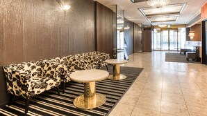 Un hall d’entrée moderne avec un canapé, deux tables rondes et un tapis à motifs.