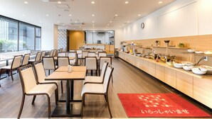 Un restaurant doté de plusieurs tables et chaises, d’un espace cuisine et d’un tapis rouge sur le sol.