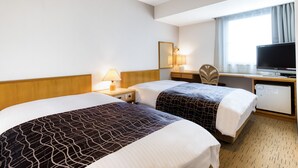 Une chambre d’hôtel avec deux lits, un bureau, une chaise, une télévision et une fenêtre avec des rideaux.