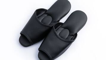 A pair of black slip-on shoes with a textured sole and a strap across the top.