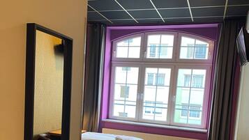 Ein Hotelzimmer mit Bett, Schreibtisch und einem Fenster mit Blick auf Gebäude.