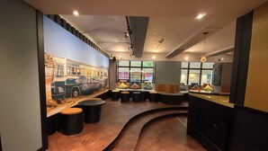 A modern interior with a curved wooden floor, seating areas, and a mural of a bus. - Singer109 Hostel (Berlin)