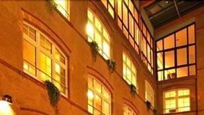A multi-story building with a warm, orange glow from the windows. - Singer109 Hostel (Berlin)