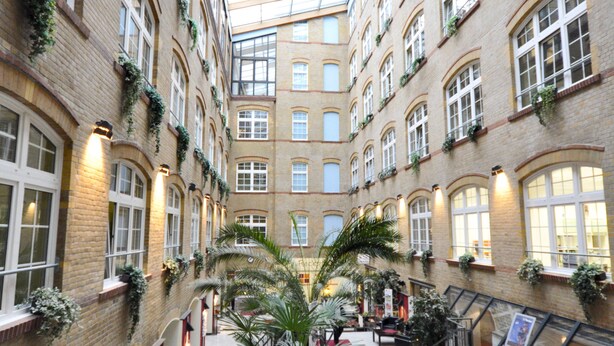 A spacious atrium with a high ceiling, multiple floors, and a central staircase. - Singer109 Hostel (Berlin)
