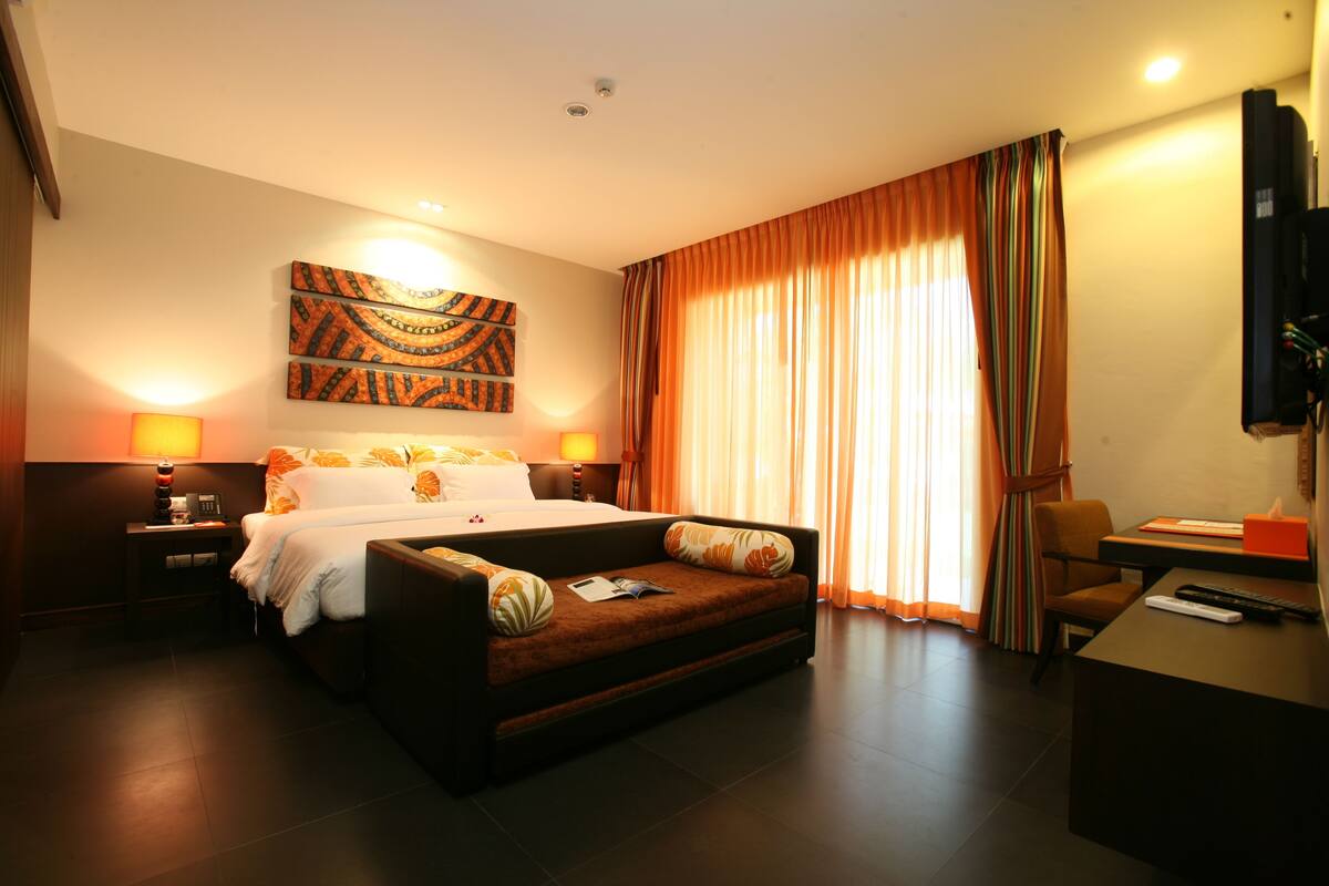 Una habitación de hotel con cama, sofá, escritorio y televisión.